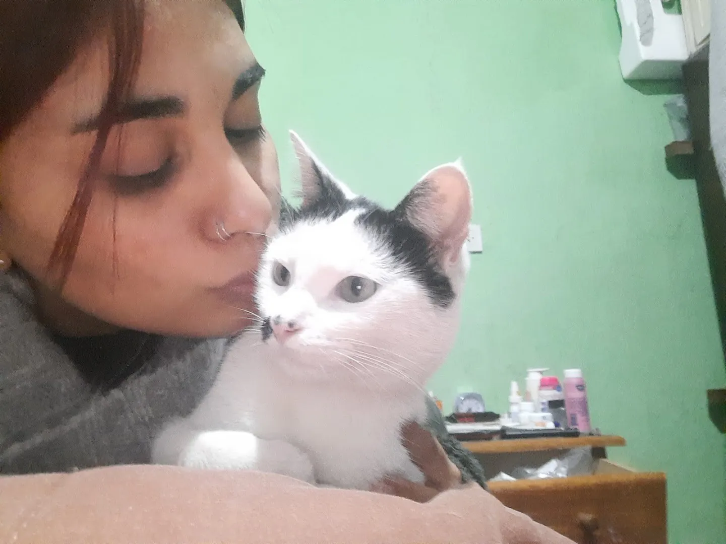 Una chica le da un beso a su gata blanca y negra
